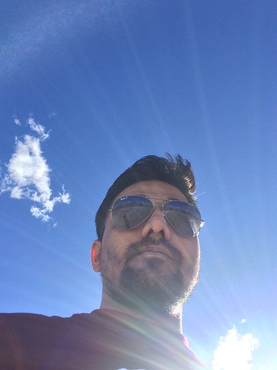 Vinaay Patil squinting into a bright blue sky, sunglasses on.