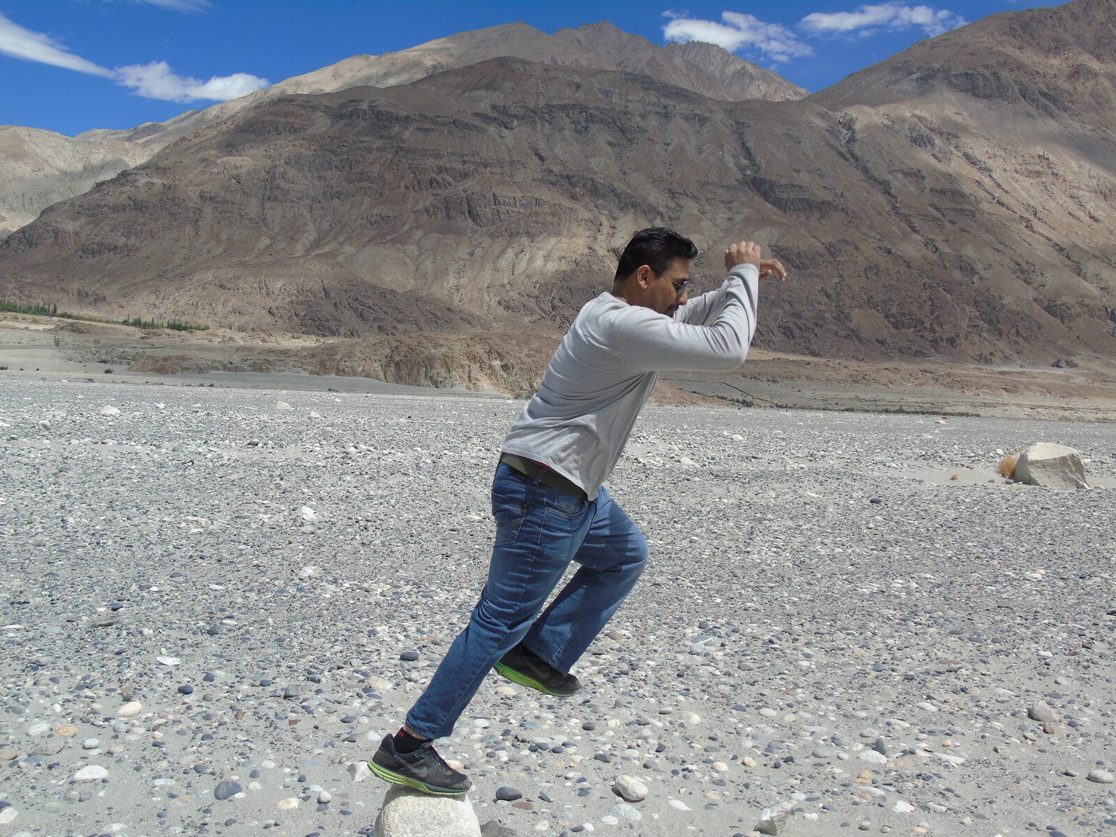 Vinaay Patil striking a playful karate pose on a rocky river bed in Nubra Valley, Ladakh.