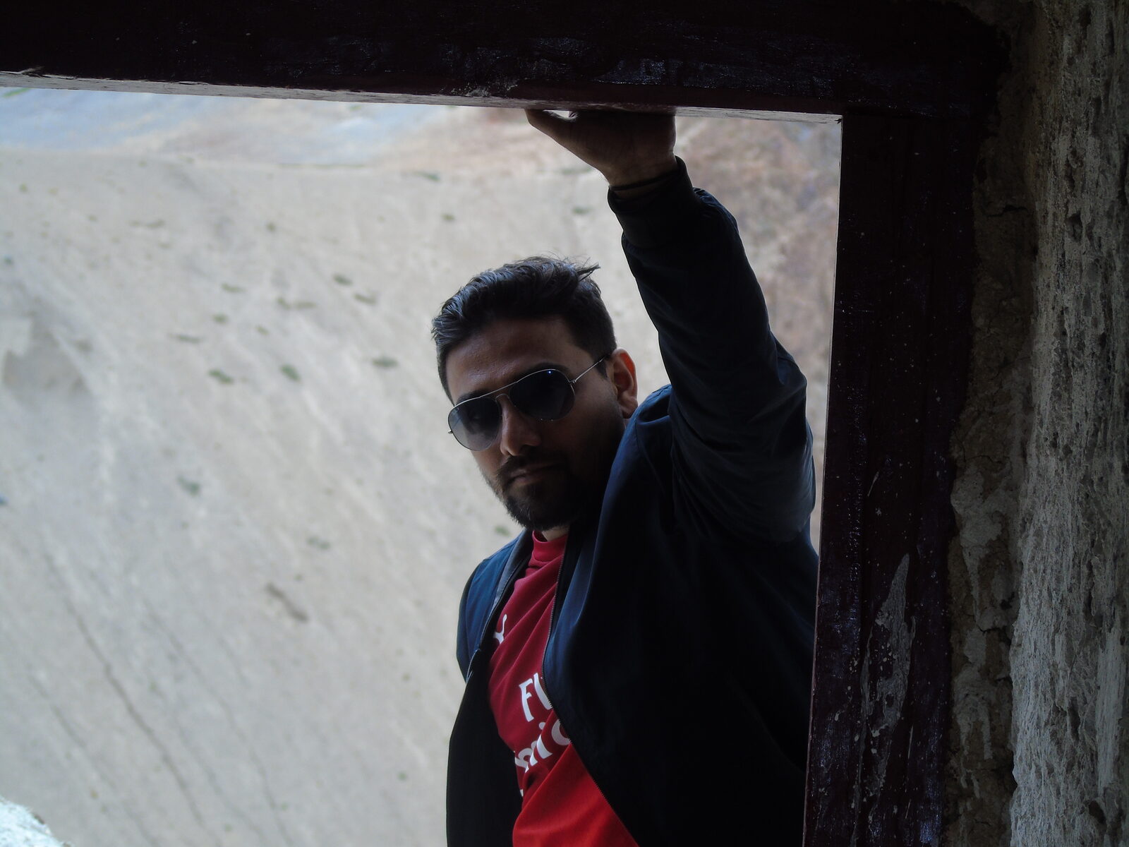 Vinaay Patil leaning in a stone doorway overlooking a mountain valley in Ladakh.